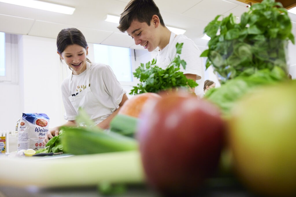 Schülerin und Schüler bereiten gemeinsam frisches Gemüse zu