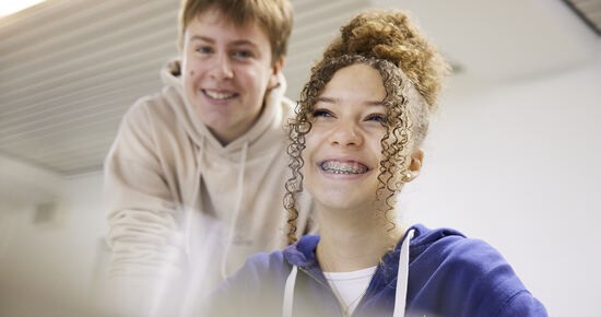 Zwei Schüler:innen lächeln in die Kamera